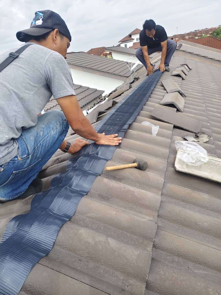 Pekerja memasang ridge flashing tape pada perabung bumbung genting